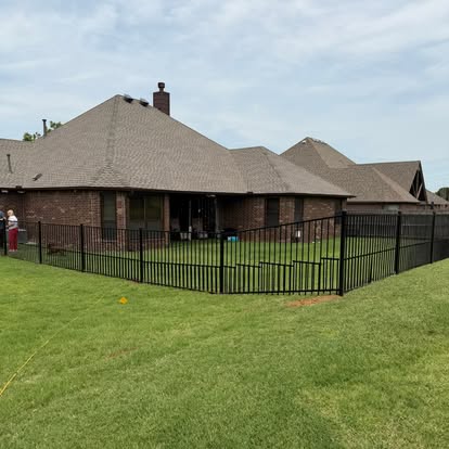 Black metal fence enclosing the back yard of a brick home
