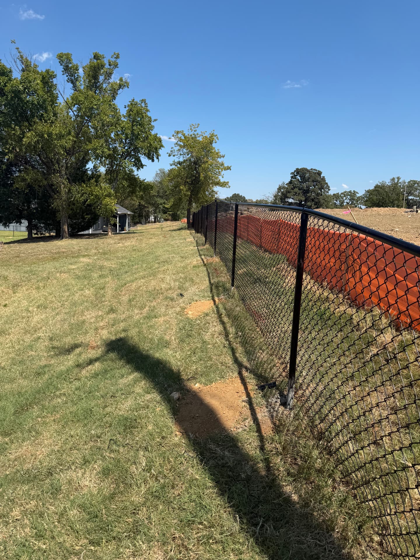 Black chain link fence along a grassy property boundary
