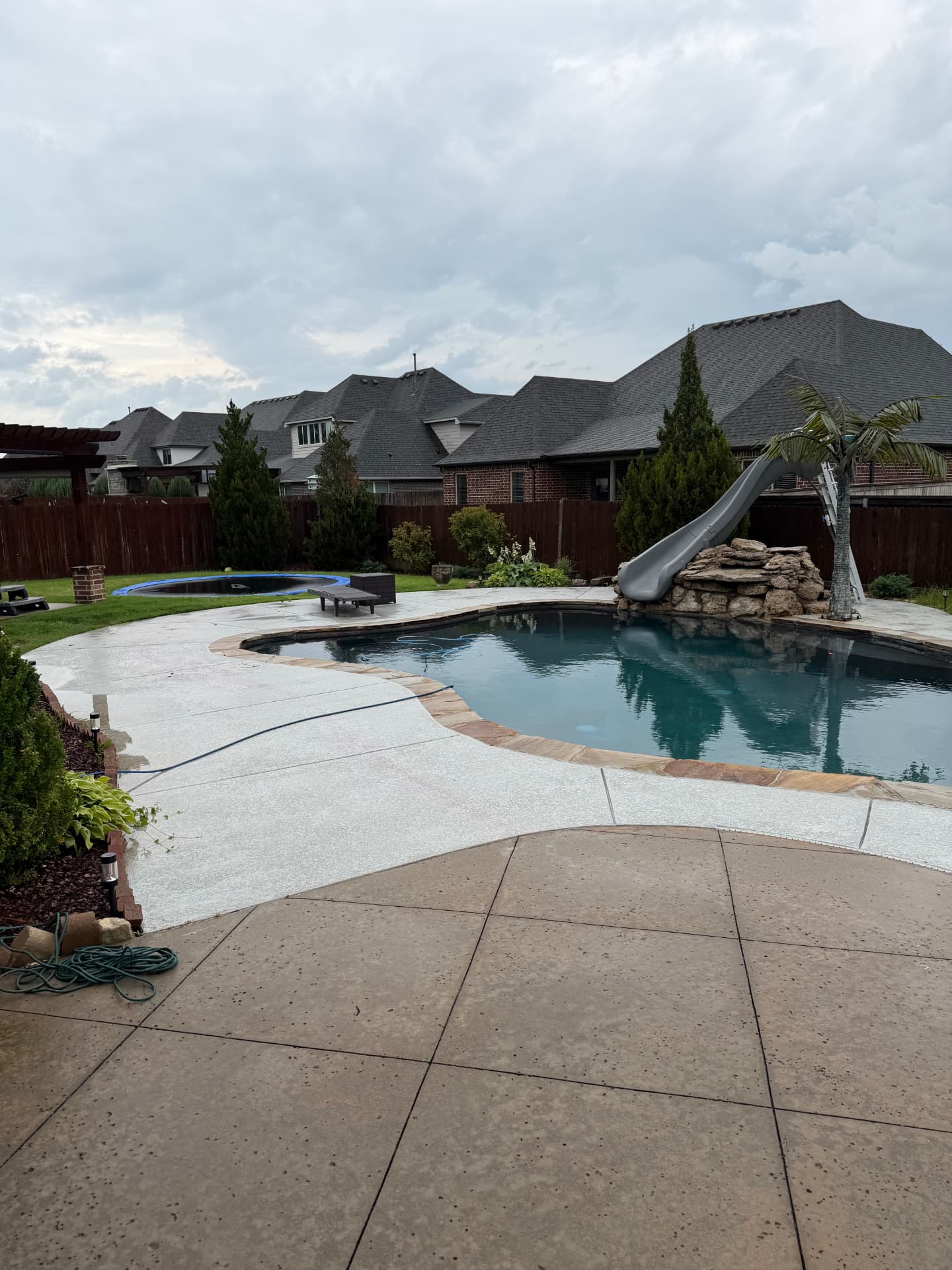 Backyard swimming pool and patio before the metal fence installation