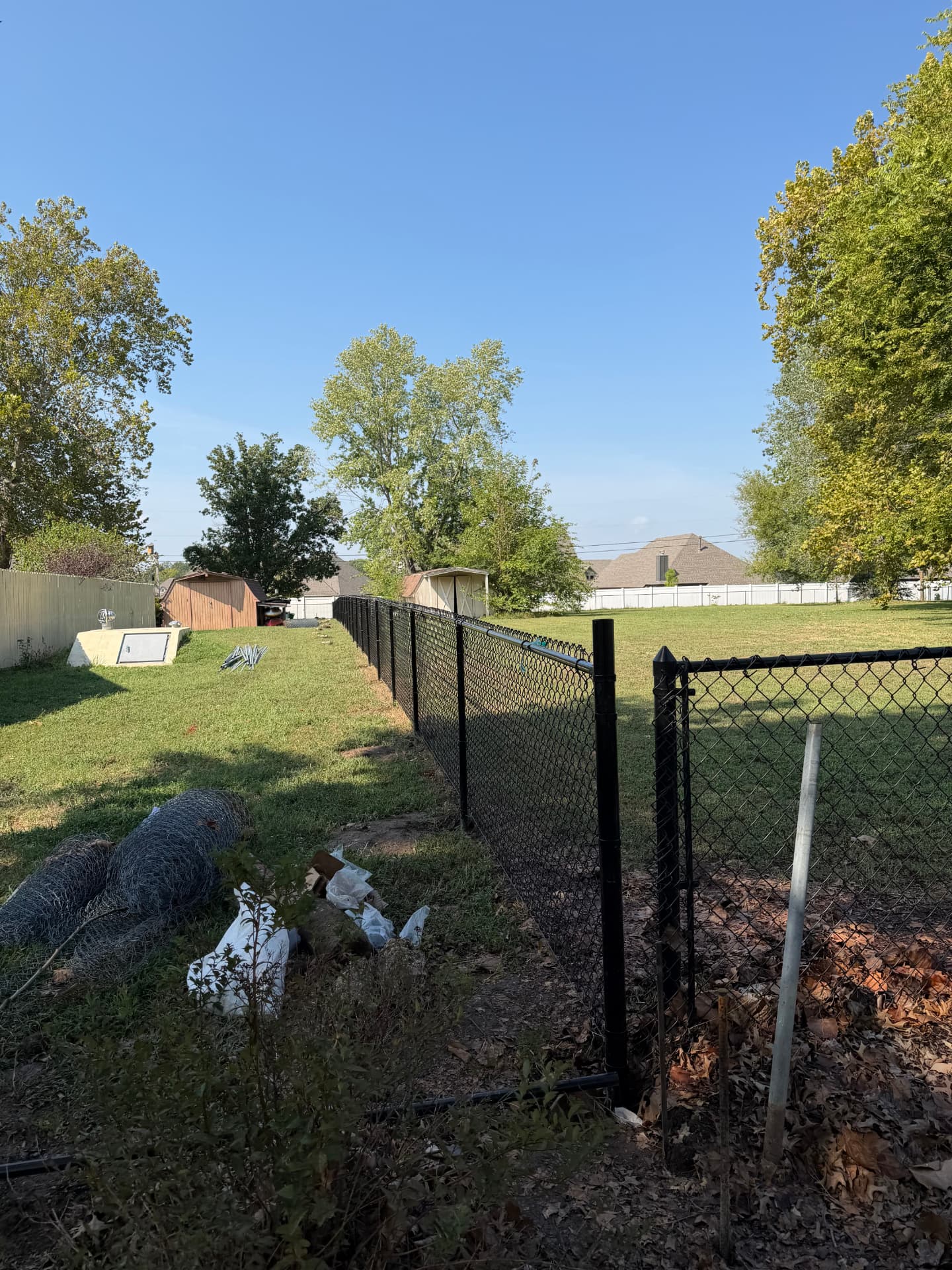 Black chain link fence and gate along a backyard boundary