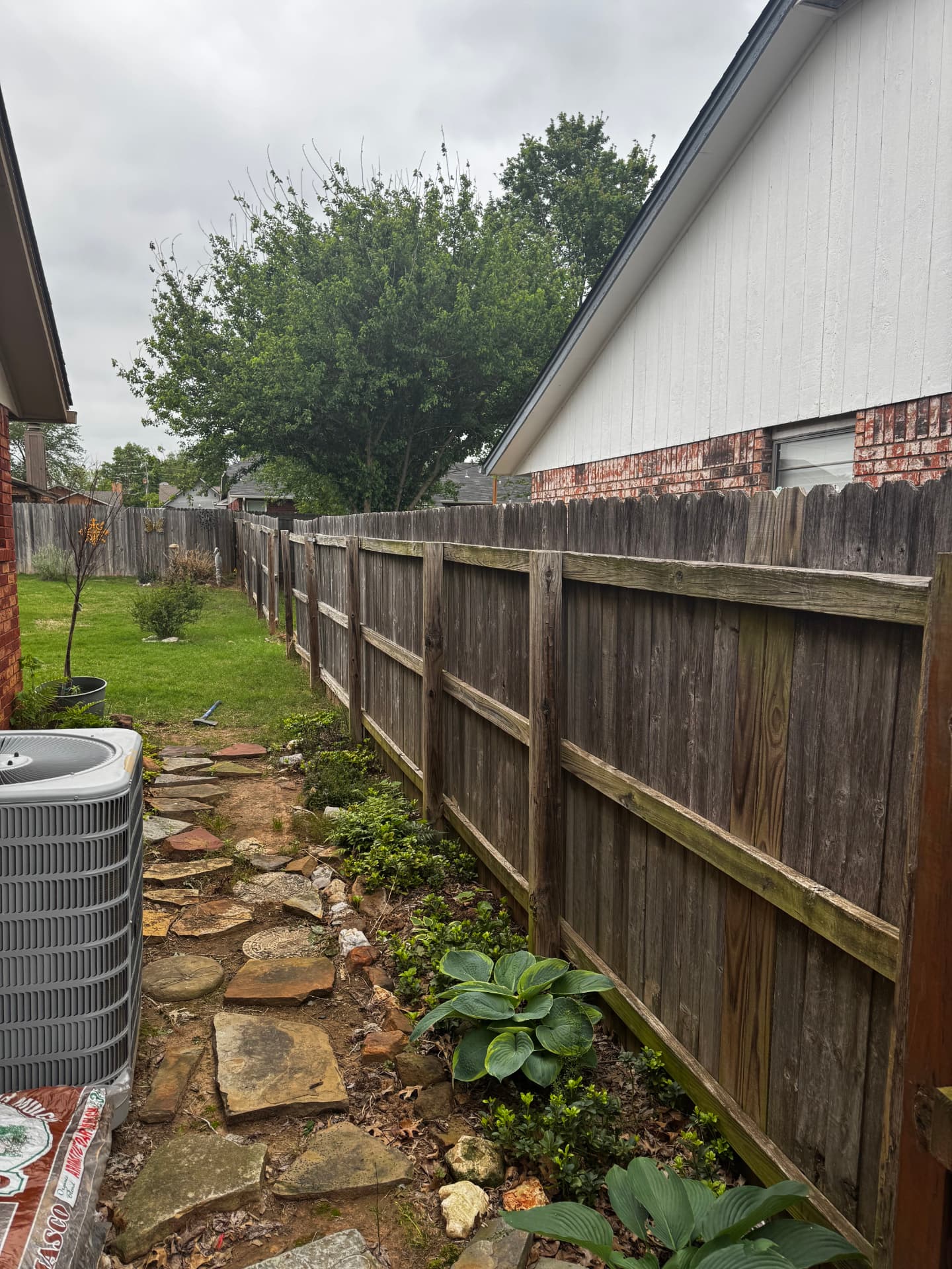 Weathered wood privacy fence beside a residential garden path