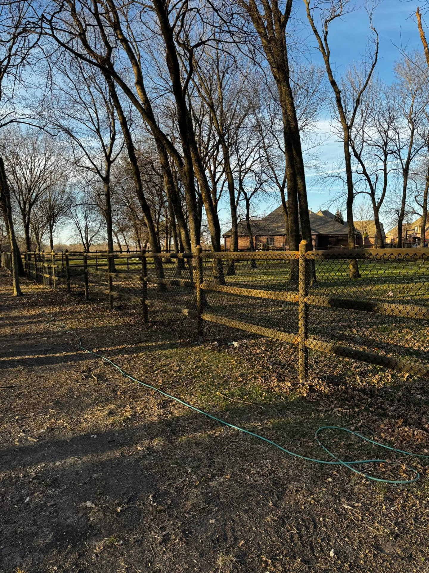 Round rail fence with wire mesh running through a wooded acreage property