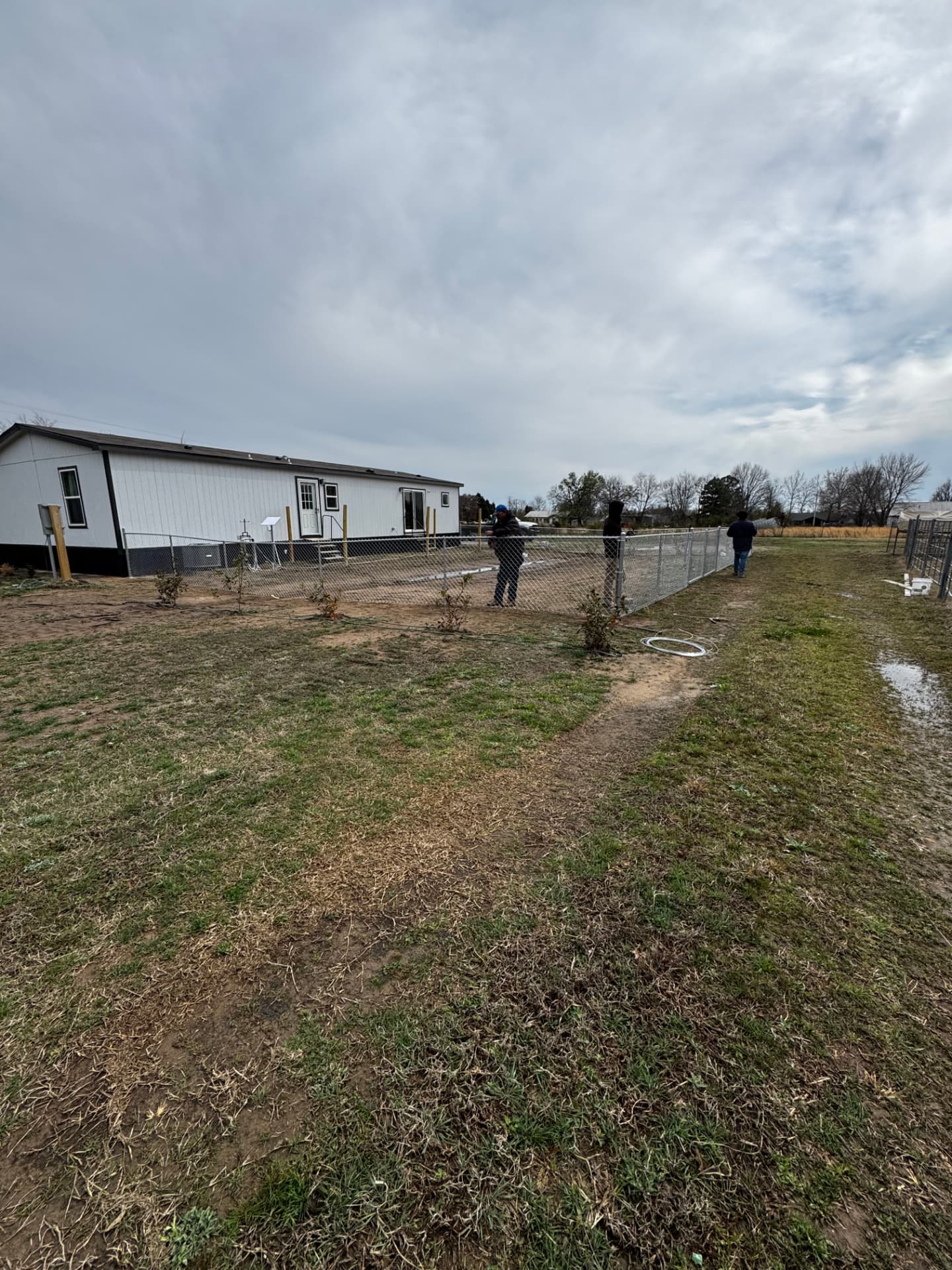 Chain link fence installation in progress beside a manufactured home